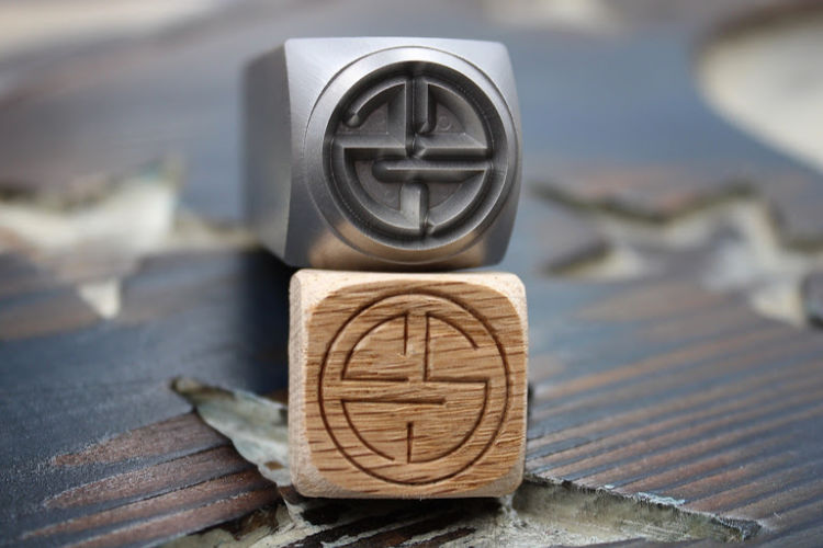 face grain wood stamped with CCS wood logo stamp with steel hand stamp used to mark it lying on top of the marked piece of wood