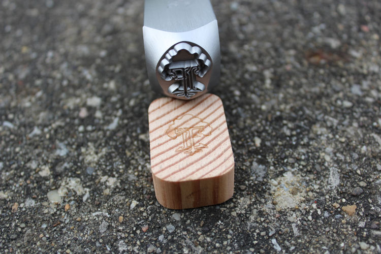 steel wood hand stamp for marking wood made by Buckeye Engraving pictured showing stamp's tree design deeply engraved in steel hand stamp and pied of end grain wood shows stamp image on it