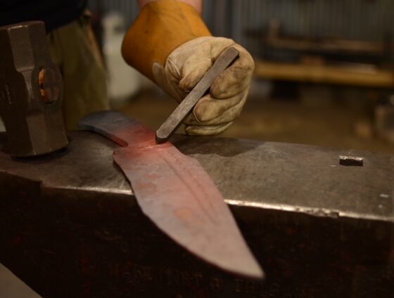 hot forged knife blade glows red while hot stamping trouchmark happens illustrates hot stamping vs cold stamping metal